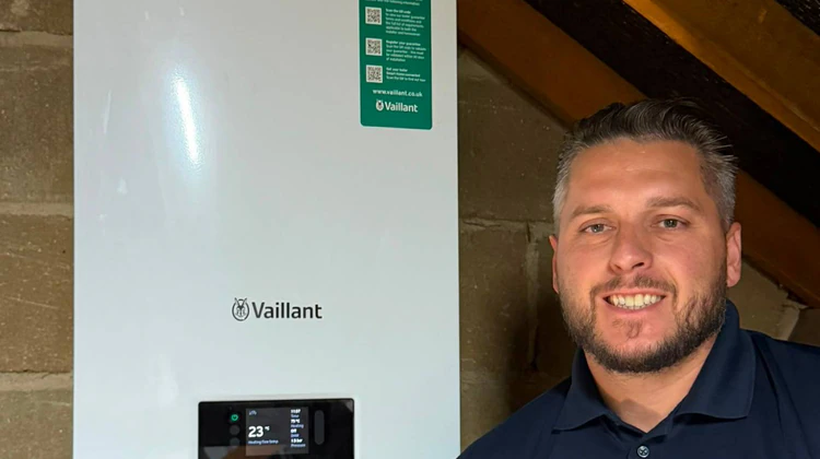 Jordan from JTS Local Boiler Expert next to a wall-mounted boiler in a loft